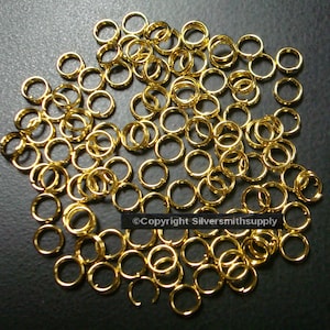 May include: A large pile of gold jump rings. The rings are all the same size and are arranged in a random pattern.  ©Copyright Silversmithsupply