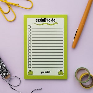 Può includere: Un blocco note verde con un'illustrazione di serpente e il testo "ssstuff to do". Il blocco note ha un elenco di controllo con 15 righe e il testo "you did it!" in fondo.