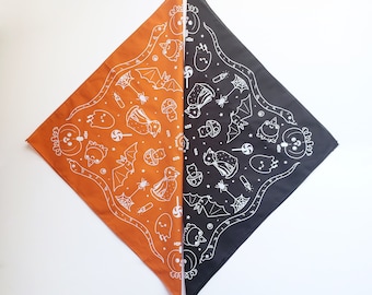 Puede incluir: Un pañuelo reversible con fondo negro y naranja. Un lado presenta un diseño blanco de una serpiente, murciélagos, fantasmas y otras imágenes de temática de Halloween. El otro lado presenta el mismo diseño en naranja sobre un fondo negro.