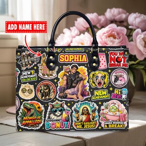 Könnte beinhalten: Schwarze Handtasche mit schwarzem Griff und einer Vielzahl farbenfroher, aufkleberähnlicher Designs. Die Designs umfassen Zeichentrickfiguren, Text und Illustrationen. Das Wort "SOPHIA" wird in gelben Buchstaben angezeigt.