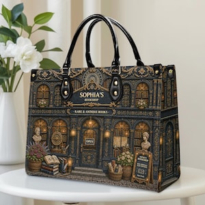 Vintage bookstore handbag shown on a clean indoor table, featuring a detailed antique bookshop design with golden accents, warm window lights, flower baskets, books, statues, black handles, and structured side panels. A charming personalized book lover bag for readers, librarians, teachers, writers, book collectors, and fans of classic literary style.