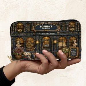 Puede incluir: Un monedero con una ilustraci&oacute;n detallada de "Sophia's Bookshop". El dise&ntilde;o muestra una fachada de librer&iacute;a vintage con detalles arquitect&oacute;nicos ornamentados, bustos y el texto "Rare & Antique Books".