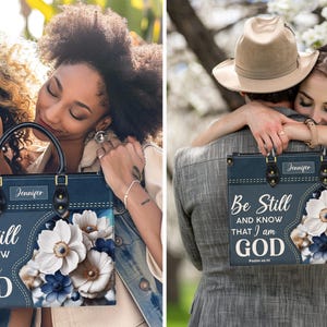 Puede incluir: Una bolsa de mano azul con un dise&ntilde;o floral y el texto "Be Still and Know That I am GOD" impreso en ella. La bolsa tiene una etiqueta de nombre personalizada que dice "Jennifer".