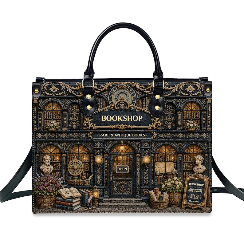 Front view of a vintage bookshop handbag on a white background, featuring an antique bookstore illustration with glowing windows, stacked books, flower baskets, ornate gold details, black handles, and a detachable shoulder strap. Perfect book lover purse, literary tote bag, librarian gift, teacher gift, writer gift, and personalized reader accessory.