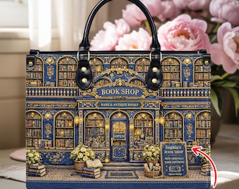 Puede incluir: Bolso azul con una ilustración detallada de una fachada de librería. El texto "BOOK SHOP" y "RARE & ANTIQUE BOOKS" son visibles. El bolso tiene un asa negra y un letrero que dice "Sophia's BOOK SHOP".