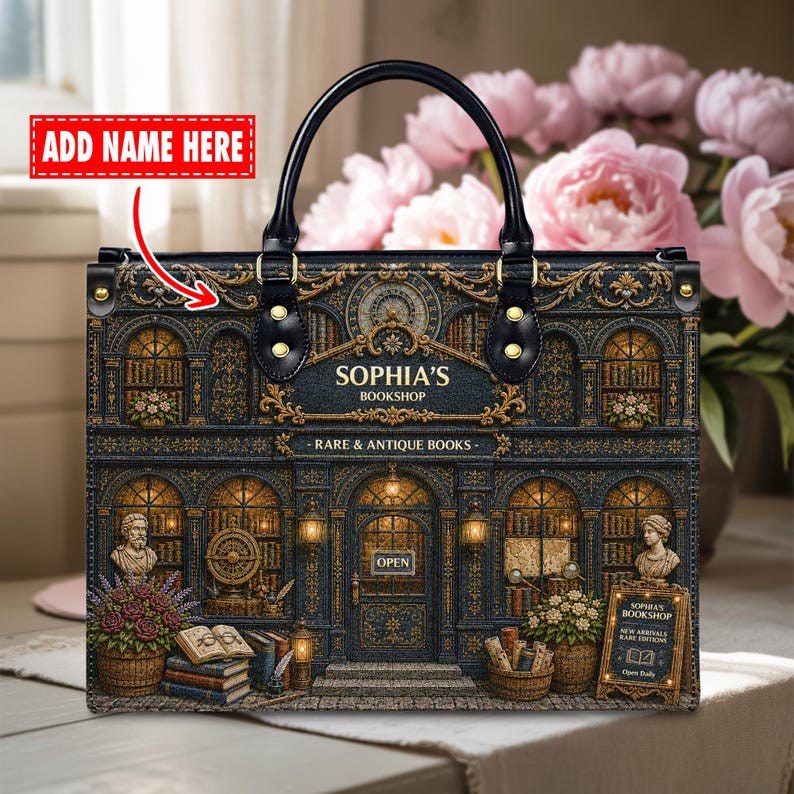 Personalized vintage bookshop handbag displayed in a cozy floral setting, featuring an antique bookstore illustration with ornate gold details, arched windows, stacked books, flowers, black handles, and custom name placement. Perfect literary tote bag for book lovers, librarians, teachers, writers, readers, book club friends, and unique personalized gift ideas.