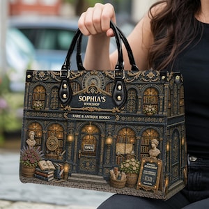 Woman holding a personalized bookshop handbag with black handles and a detailed vintage bookstore print, featuring arched windows, stacked books, flowers, gold ornamental details, and antique library charm. Great everyday literary handbag for book lovers, teachers, librarians, writers, readers, book club members, and thoughtful custom gifts.