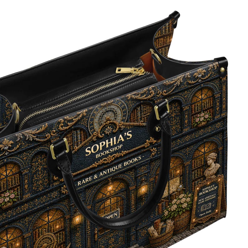Puede incluir: Bolso tote negro con un estampado detallado de una fachada de librer&iacute;a. El bolso presenta el texto "SOPHIA'S BOOKSHOP" y "RARE & ANTIQUE BOOKS". Tiene una cremallera dorada y asas negras.