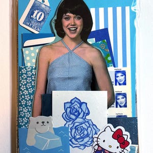 Mystery ephemera pack in Blue, showing vintage texts, picture of woman in blue halter tank top from a sewing pattern, decorative papers, art print with blue roses, cancelled postage stamp, glitter paper, and stickers.