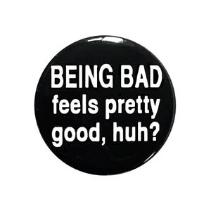 Pode incluir: Botão preto com texto branco que diz "BEING BAD feels pretty good, huh?"