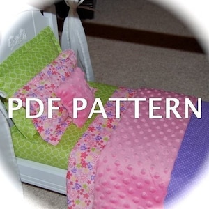 Puede incluir: Una cama de muñecas con ropa de cama, que incluye una sábana verde estampada, una almohada rosa con estampado floral y una manta rosa texturizada. El texto "PDF PATTERN" está superpuesto en la imagen.