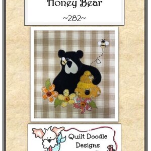 May include: A black bear applique with a honey pot and flowers on a checkered background. The text "Honey Bear ~282~" is at the top of the image. The text "Quilt Doodle Designs" is at the bottom of the image.
