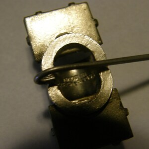 Puede incluir: Primer plano de un eslab&oacute;n de cadena de metal plateado con un peque&ntilde;o anillo de metal. El eslab&oacute;n de cadena est&aacute; unido a una barra de metal con un peque&ntilde;o lazo de metal.