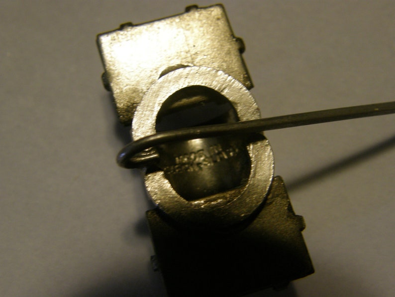 Puede incluir: Primer plano de un eslab&oacute;n de cadena de metal plateado con un peque&ntilde;o anillo de metal. El eslab&oacute;n de cadena est&aacute; unido a una barra de metal con un peque&ntilde;o lazo de metal.