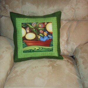 May include: Green pillow with a colorful illustration of a person in a boat surrounded by flowers and a green background.