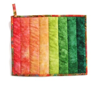 May include: A colorful quilted hot pad with a rainbow pattern of red, orange, yellow, green, and blue. The hot pad has a loop for hanging.