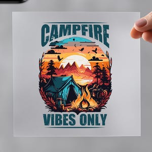 May include: A white t-shirt with a heat transfer featuring a colorful camping scene with the text "Campfire Vibes Only." An iron and the words "Easy to Press" are also visible.