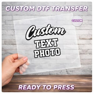 May include: A clear, rectangular DTF transfer sheet with the words "Custom Text Photo" in black and white. The sheet is held by a hand and has the text "Custom DTF Transfer" and "Ready to Press" in a purple font.
