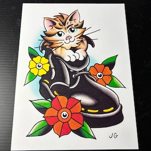 Puede incluir: Ilustración estilo tatuaje de un gato en una bota negra, rodeado de flores coloridas. El gato es naranja y marrón con ojos azules. Las flores son amarillas, naranjas y rojas con hojas verdes. La obra está sobre papel blanco.