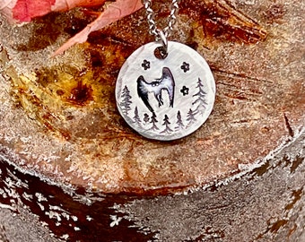 May include: A silver necklace with a round pendant featuring a stylized owl with outstretched wings in a forest setting. The pendant has a hammered texture and is surrounded by small stars.