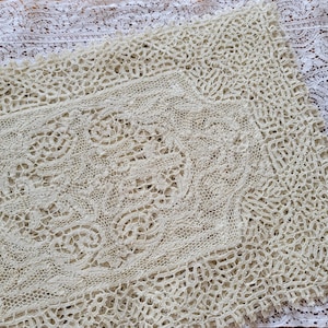 May include: Close-up of two cream-colored lace textiles. The lace features intricate floral and geometric patterns. The textiles are likely used for home decor or craft projects. The lace has a delicate, open weave.