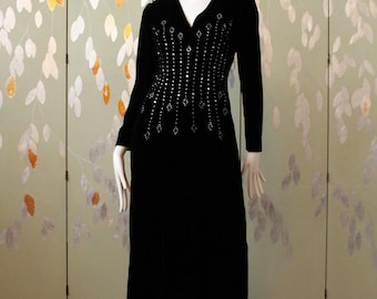 May include: A long black velvet dress with a beaded design on the bodice. The dress is on a mannequin in front of a green and gold patterned screen.