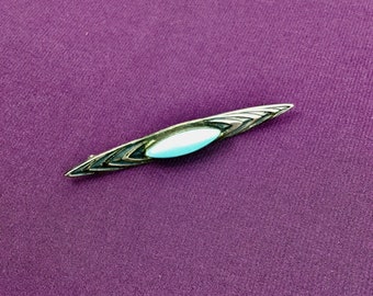 May include: A silver brooch with a turquoise oval stone set in a geometric design.