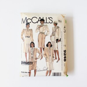 Peut inclure: Un patron de couture McCall's vintage de 1984, avec des illustrations de tenues féminines sur le thème de Dynasty. Le paquet est beige avec du texte et des illustrations noirs. Le prix est de 4,75 $.