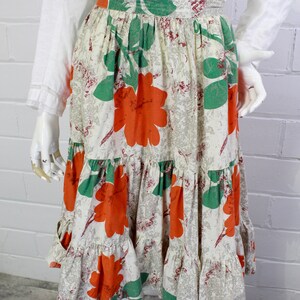 May include: A tiered skirt with a white background and a large floral print in shades of orange and green.