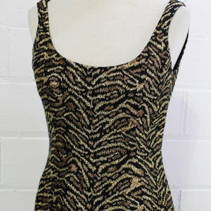 May include: A sleeveless dress with a black and gold zebra print. The dress is made of a sparkly fabric.