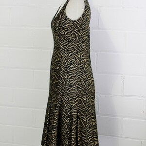 May include: A sleeveless dress with a black and gold animal print. The dress has a fitted bodice and a flowing skirt.