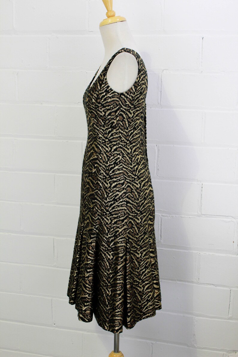May include: A sleeveless dress with a black and gold animal print. The dress has a fitted bodice and a flowing skirt.