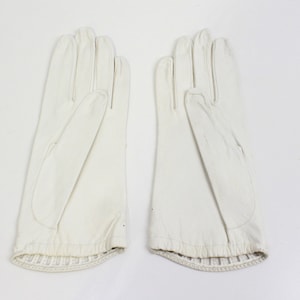 May include: A pair of white leather gloves with a ribbed cuff.