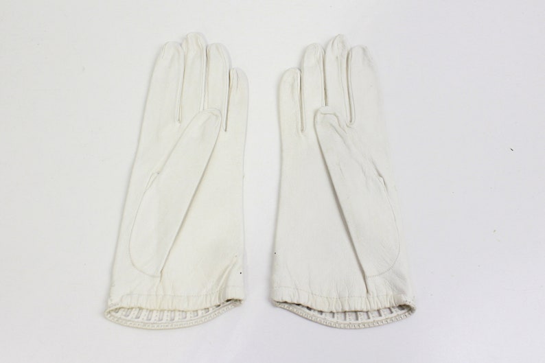 May include: A pair of white leather gloves with a ribbed cuff.
