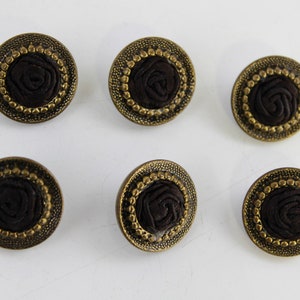 Peut inclure: Six boutons ronds de couleur marron et or avec un motif de rose en relief texturé. Les boutons ont un bord doré avec un bord perlé.