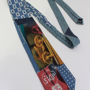 May include: A patterned necktie with a patchwork design. The tie features various patterns, including blue squares, polka dots, and a bicycle graphic. The bottom of the tie has a red stop sign graphic. The tie is made of a soft fabric.