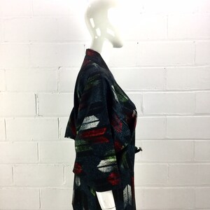 May include: A black and green patterned kimono with red, white, and green accents. The kimono is made of a soft, woven fabric and has a relaxed fit.