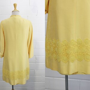 May include: A yellow dress with a lace trim. The dress has a long sleeve and a fitted bodice. The lace trim is a delicate floral pattern.