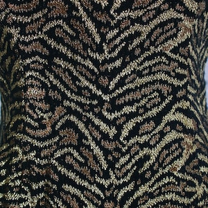 May include: Black fabric with a gold and brown zebra print pattern.
