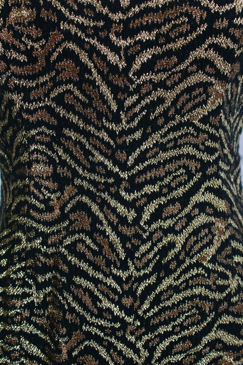 May include: Black fabric with a gold and brown zebra print pattern.