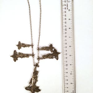 May include: A silver necklace with a pendant featuring a stylised female figure and several smaller pendants in the shape of stylised flowers. The necklace is approximately 28 inches long.