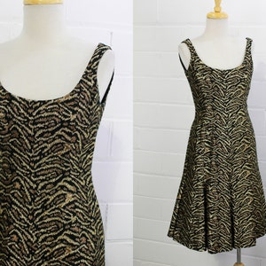 May include: A sleeveless dress with a black and gold animal print. The dress has a scoop neck and a flared skirt.