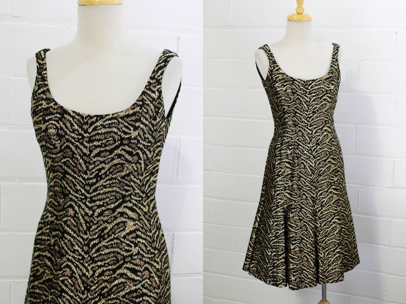 May include: A sleeveless dress with a black and gold animal print. The dress has a scoop neck and a flared skirt.