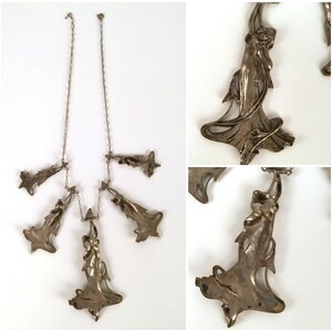 May include: A silver necklace with five pendant charms, each featuring a stylised female figure in a flowing gown. The charms are connected to a delicate silver chain.