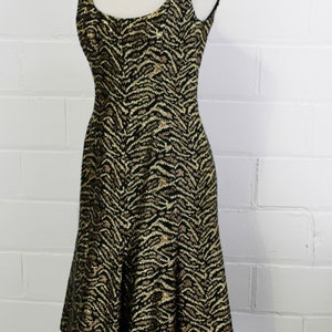 May include: A sleeveless dress with a black and gold zebra print. The dress has a fitted bodice and a flared skirt.