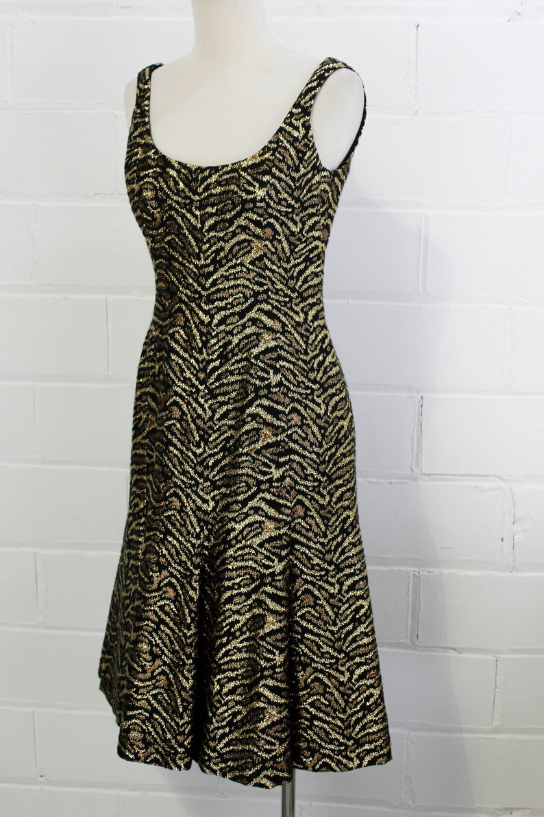 May include: A sleeveless dress with a black and gold zebra print. The dress has a fitted bodice and a flared skirt.