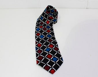 May include: A black tie with a geometric pattern of white diamonds and red and blue circles.