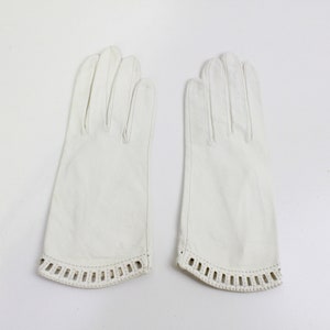 May include: A pair of white leather gloves with a decorative lace trim around the wrist.
