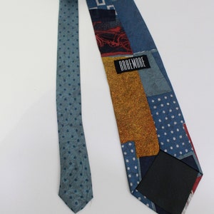 May include: A patterned necktie with a variety of blue hues and a polka dot design. The tie features a patchwork design with squares, rectangles, and a bicycle graphic. The label reads "BRAEMORE".