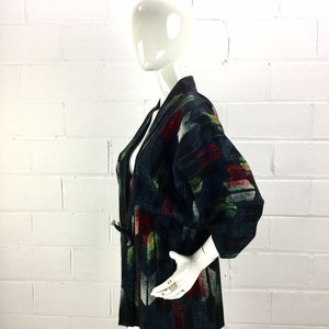 May include: A black and green patterned kimono with a long sleeve and a tie belt. The kimono is made of a soft, textured fabric.